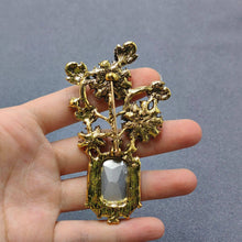 Load image into Gallery viewer, Gold brooch held in a hand against a gray background
